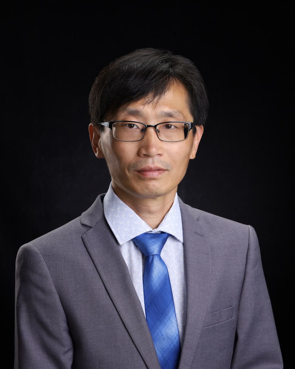 Asian man in a suit and tie posing for a photo in Alberta.