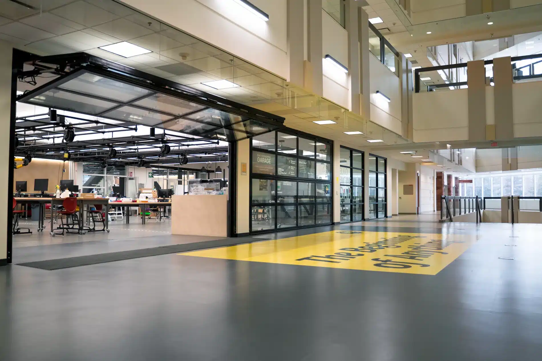 A hallway equipped with advanced nanofabrication technology and AI that features a vibrant yellow sign and floor.
